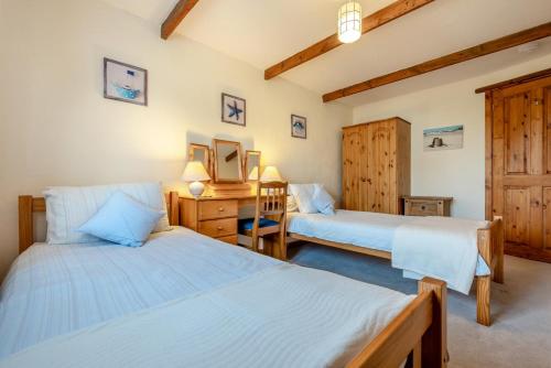 a bedroom with two beds and a desk with a mirror at Mallard Cottage - Padstow in St Merryn