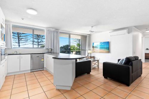 a kitchen with a table and a couch in a room at Northwind Beachfront Apartments in Mooloolaba