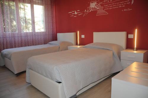 two beds in a bedroom with red walls at Affittacamere La Perla in La Spezia