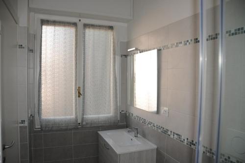 a white bathroom with a sink and a mirror at Affittacamere La Perla in La Spezia