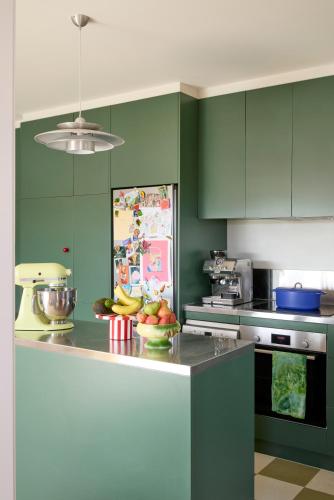 a kitchen with green cabinets and a bowl of fruit on a counter at Designer Bondi apartment - walk to beach! in Sydney