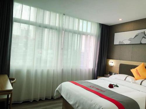 a bedroom with a large bed and a window at Jun Hotel Guangdong Zhanjiang Xiashan South Railway Station in Zhanjiang