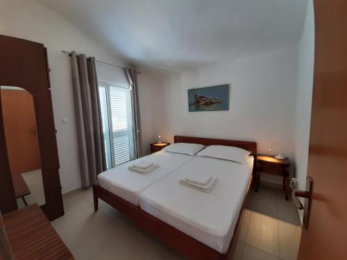 a bedroom with a bed with white sheets and a window at SEA YA - two apartments house with heated pool - 150m from beach in Zaglavice