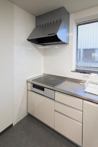 a kitchen with white cabinets and a stove top oven at Fukunosumika - Vacation STAY 79527v in Nanto