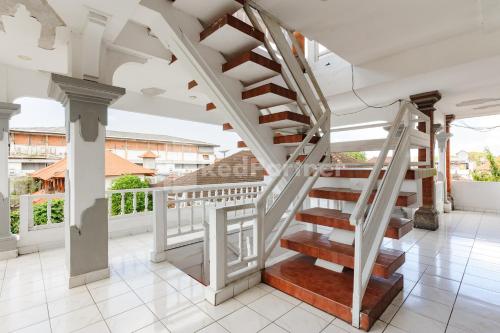 a spiral staircase in a house with a balcony at Pulau Bali Hotel Denpasar RedPartner in Denpasar