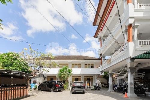 a white building with cars parked in a parking lot at Pulau Bali Hotel Denpasar RedPartner in Denpasar