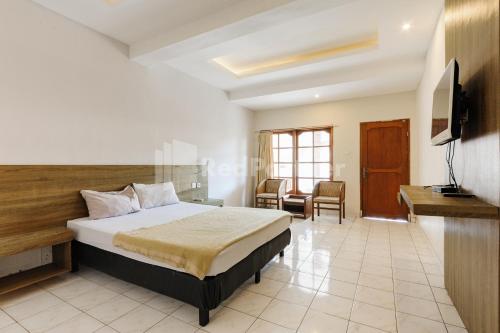 a bedroom with a bed and a desk and a television at Pulau Bali Hotel Denpasar RedPartner in Denpasar