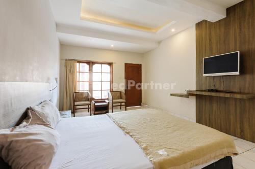 a bedroom with a bed and a tv on the wall at Pulau Bali Hotel Denpasar RedPartner in Denpasar