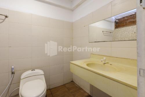 a bathroom with a white toilet and a sink at Pulau Bali Hotel Denpasar RedPartner in Denpasar