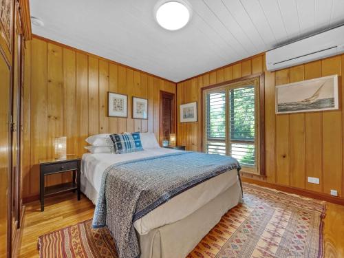a bedroom with a bed in a room with wooden walls at Luxurious Mountain Retreat near Maleny in Booroobin