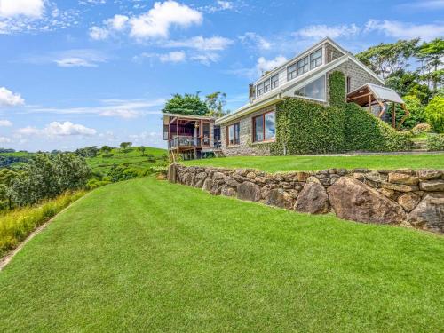 a house on a hill with a stone wall at Luxurious Mountain Retreat near Maleny in Booroobin