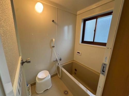 a bathroom with a shower and a toilet and a window at みんぱく明治村 in Tome