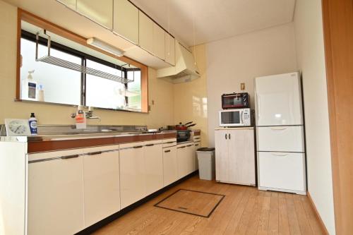 a kitchen with white cabinets and a white refrigerator at みんぱく明治村 in Tome