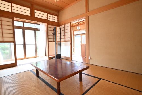 a room with a wooden table in a room with windows at みんぱく明治村 in Tome