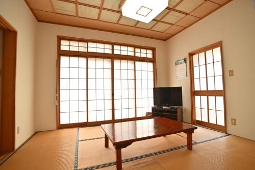 a living room with a coffee table and large windows at みんぱく明治村 in Tome