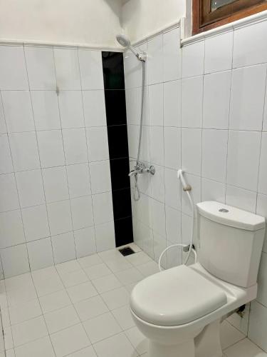 a white bathroom with a toilet and a shower at Highest Village Bungalow in Nuwara Eliya