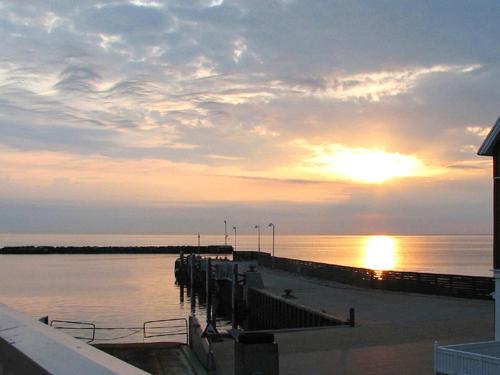 a sunset over the water with a pier and the ocean at 6 person holiday home in Bagenkop in Bagenkop