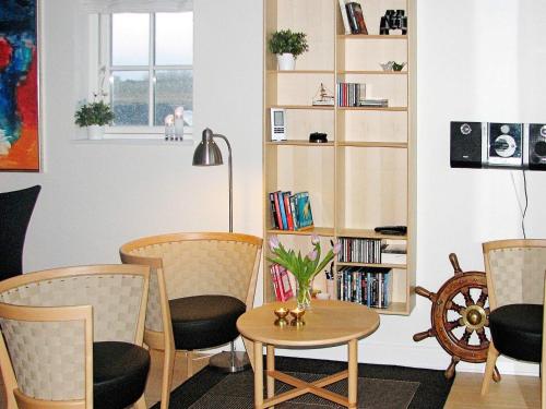 a living room with chairs and a table and a book shelf at 6 person holiday home in Bagenkop in Bagenkop