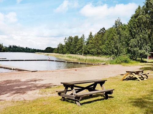 two picnic tables on a beach near a body of water at 6 person holiday home in GAMLEBY-By Traum in Gamleby