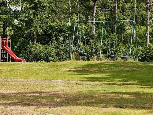 a playground with a swing set in a park at 6 person holiday home in GAMLEBY-By Traum in Gamleby
