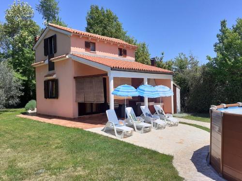 a house with a group of chairs and umbrellas at Charming Pool Home Near Pula in Pula