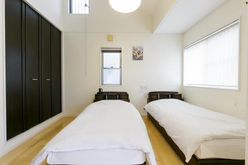 two beds in a room with white walls and a window at HANA - Vacation STAY 18403 in Nagoya