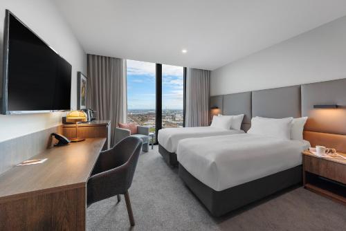 a hotel room with two beds and a flat screen tv at Oakwood Premier Melbourne in Melbourne