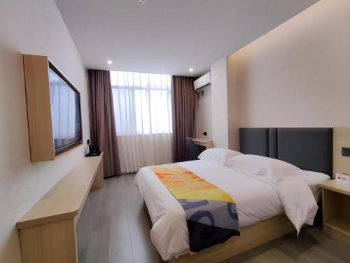 a bedroom with a large bed and a television at Shell Hotel Wuxi Huishan District Chang'an Town in Wuxi