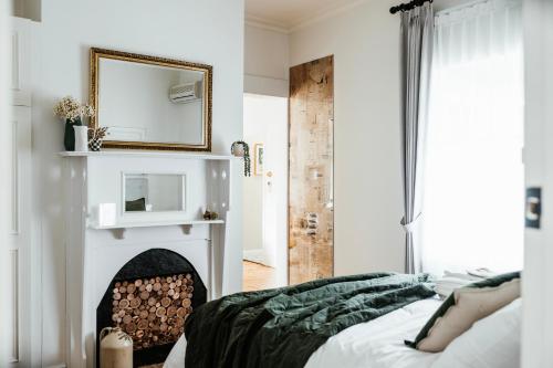a bedroom with a fireplace with a mirror and a bed at Historic Benambra Boutique Hotel Queenscliff c1883 in Queenscliff