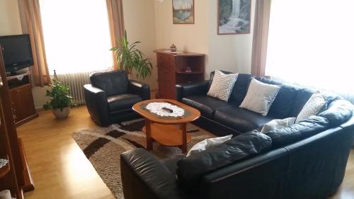 a living room with a couch and two chairs and a table at FaDóra Apartman in Tihany