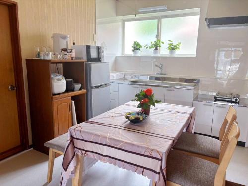 a kitchen with a table with a vase of flowers on it at kitagunihouse noboribetsu in Noboribetsu