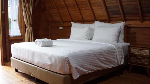 białe łóżko z ręcznikiem na górze w obiekcie Lopo Hotel & Resort Samosir w mieście Tomok