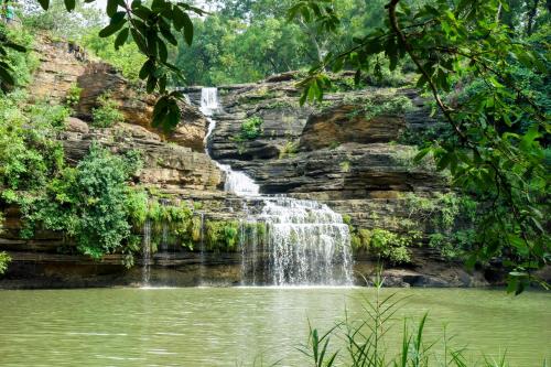 a waterfall in the jungle next to a pond at Vindhyavan Mud House in Panna