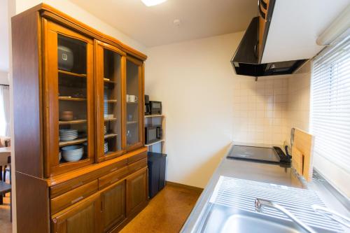 a kitchen with a wooden cabinet and a sink at ObihiroINN - Vacation STAY 18480 in Obihiro
