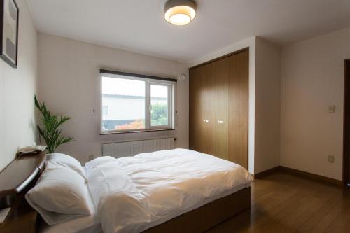 a bedroom with a large bed with a window at ObihiroINN - Vacation STAY 18480 in Obihiro
