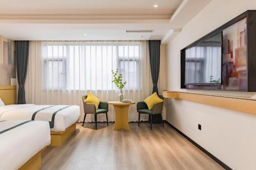 a hotel room with two beds and a table and chairs at City Comfort Inn Kunming Dashuying Yejin Hospital Wangdaqiao in Kunming