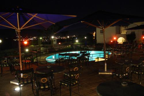a swimming pool with tables and umbrellas at night at Golden Carthage Residences in Gammarth