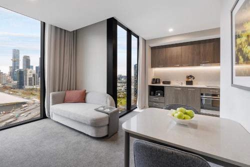 a living room with a table and a chair and a kitchen at Oakwood Premier Melbourne in Melbourne