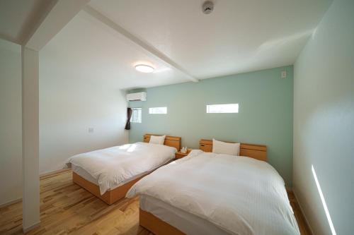 two beds in a room with blue walls and wooden floors at Yufuin Sora - Vacation STAY 23008v in Yufuin