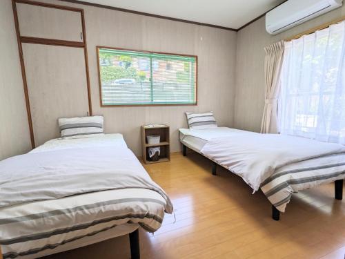 two twin beds in a room with a window at Minpaku ROADHOUSE - Vacation STAY 20160v in Nagasaki