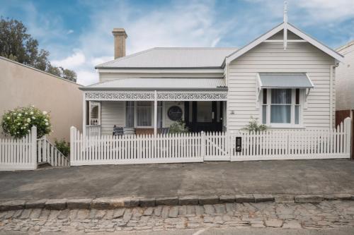 a white house with a white picket fence at Historic Benambra Boutique Hotel Queenscliff c1883 in Queenscliff