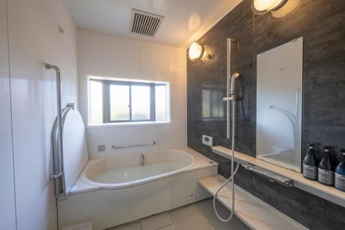 a bathroom with a tub and a shower and a sink at Kominka COCONE - Vacation STAY 18597 in Hashima