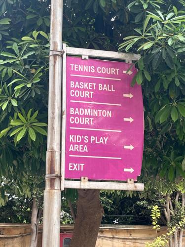 a sign for a tennis court in front of a tree at Perfect Apartment Stay in Gurgaon