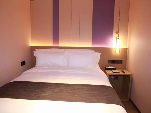 a bedroom with a bed with white pillows and a table at Lavande Hotel Shenzhen East Gate Wanxiang City Guomao Metro Statipn in Shenzhen