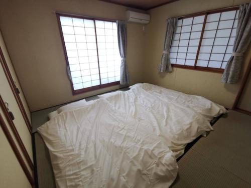an unmade bed in a room with two windows at Ocean View Escape - Vacation STAY 43308v in Jōnouchi