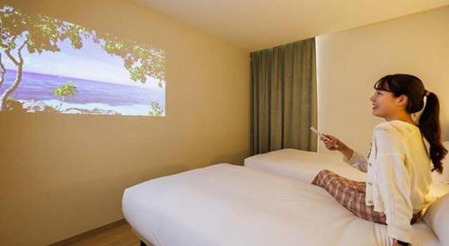 a woman sitting on a bed in a hotel room at Hotel Dream Gate Maihama in Chiba