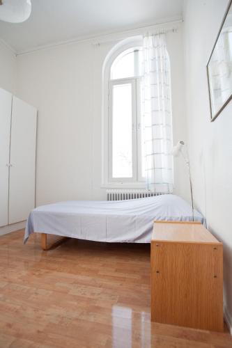 a bed in a white room with a window at Hellidens Slott in Tidaholm