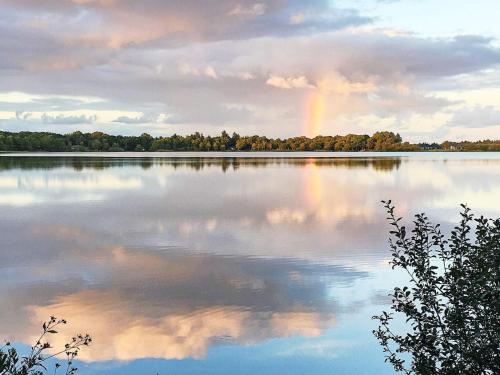 a rainbow reflecting on a lake with trees at 8 person holiday home in Ansager-By Traum in Ansager