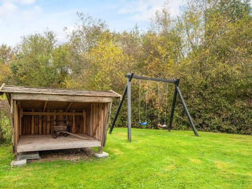 a wooden playground with a swing in a field at 8 person holiday home in Ansager-By Traum in Ansager