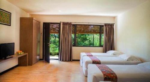 a hotel room with two beds and a television at Sambi Resort, Spa & Resto in Yogyakarta